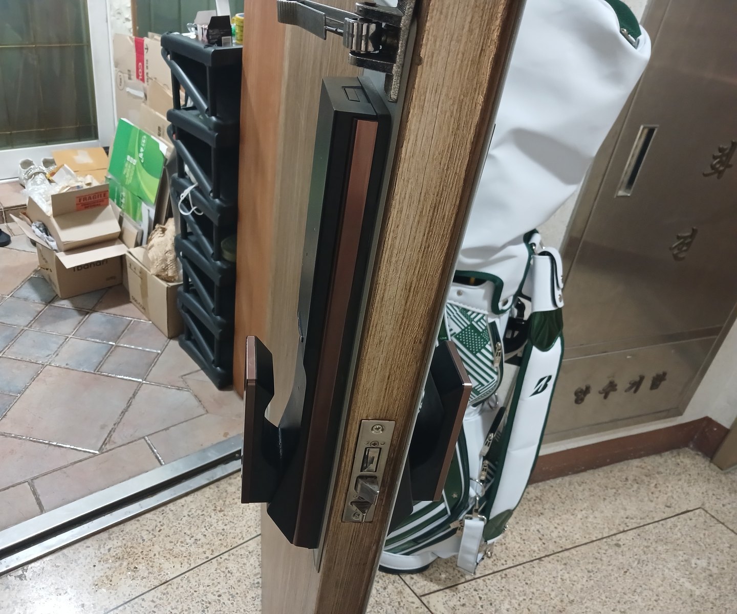 강남구 청담동 출장 — 열어 둔 나뭇결 문 안쪽의 검은 푸시풀 도어락과 문 옆면 걸쇠